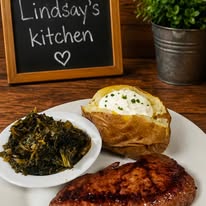 Steak dinner with baked potato and greens